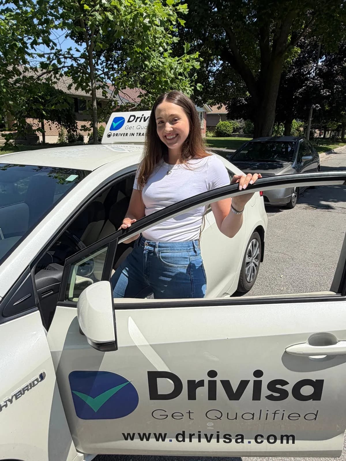 A newly licensed Drivisa graduate beside her training car